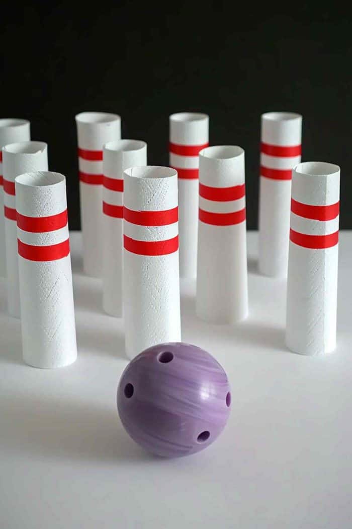 Construct a miniature bowling alley using toilet paper rolls as pins. Paint them white with two red stripes at the neck, resembling traditional bowling pins. 