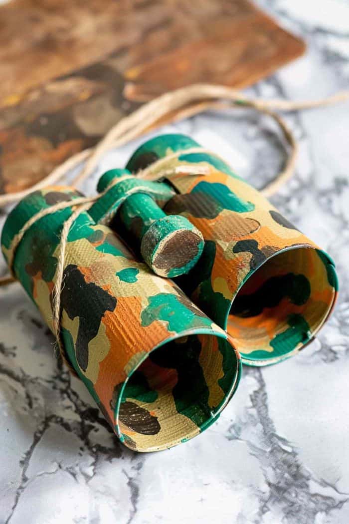 Transform a pair of toilet paper rolls into safari binoculars by painting them in green, brown, and black splotches to mimic a camouflage effect. 