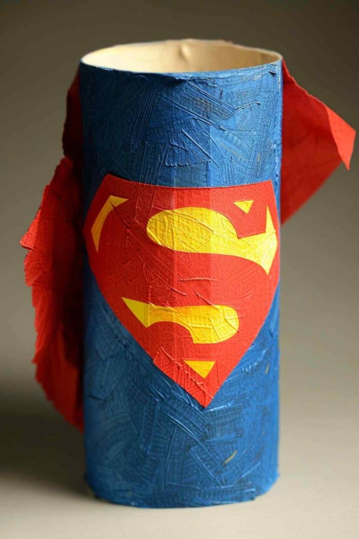 Make a Superman figure by covering a toilet roll in blue paper or paint. Cut the iconic "S" symbol from red and yellow paper and glue it to the front. Create a cape from red fabric or paper to attach at the back.