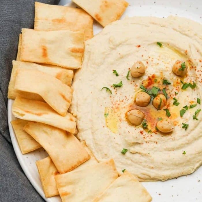 this roasted garlic hummus is the perfect choice, with classic components like chickpeas, tahini, and roasted garlic blended up in a Vitamix to create a smooth and spreadable delight