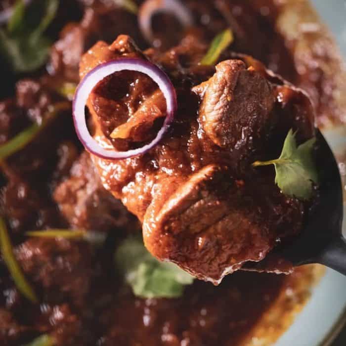 In this recipe, lamb chunks are imbued with the aromatic flavors of spices like cardamom, bay leaves, dhana jeera, and cumin seeds in a rich sauce made with a ginger-and-garlic paste, tomatoes, and caramelized onions. 