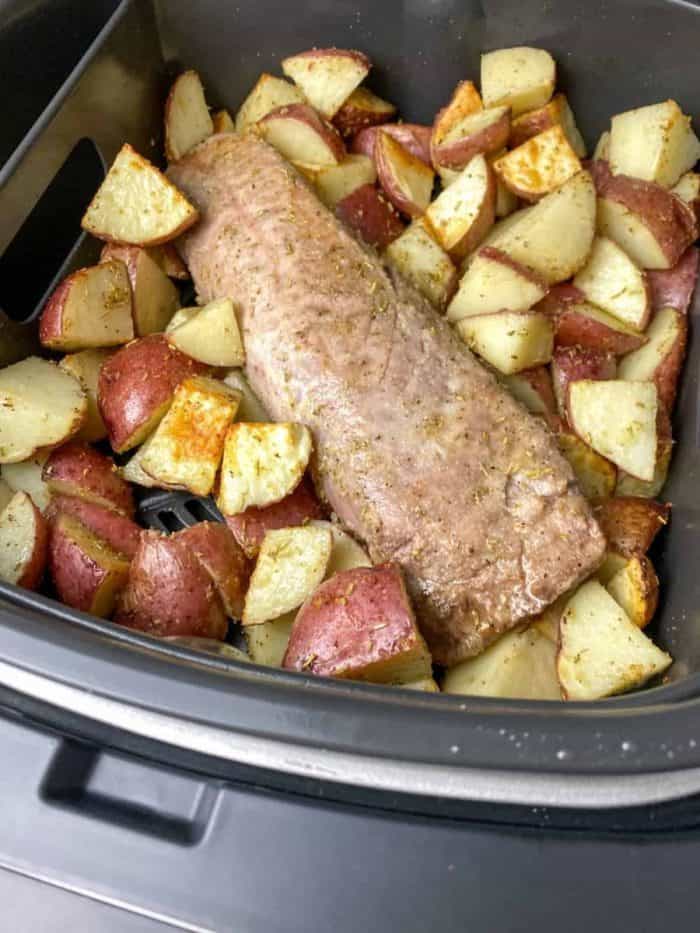 open the air fryer to flip the tenderloin and shuffle the potatoes for an even roast