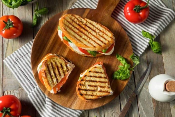 freshly cooked Healthy Grilled Basil Mozzarella Caprese Panini Sandwich placed on a wooden board