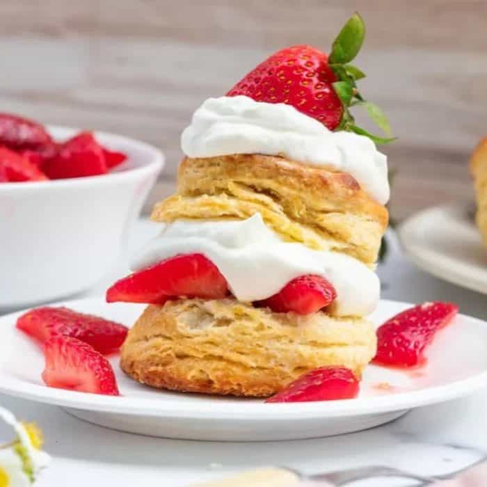 Sourdough Strawberry Shortcakes topped with fresh strawberries and placed on a white table