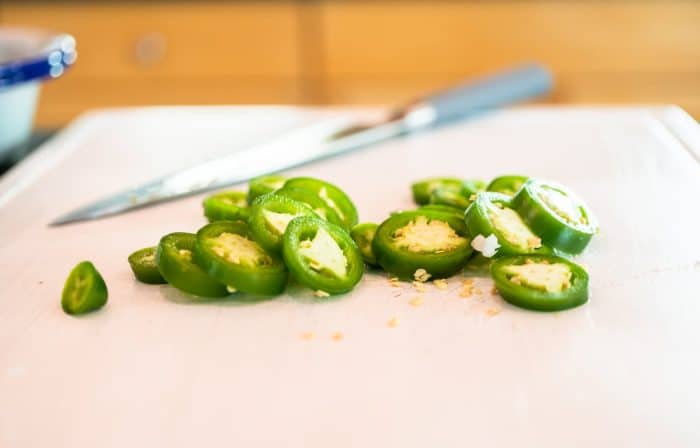 Take one jalapeño pepper, remove the stem and seeds, and slice it. Cut the other jalapeño pepper into 12 thin rings and set them aside.