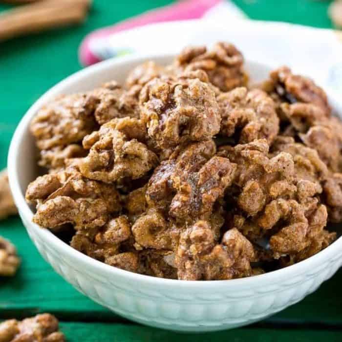 a bowl of candied walnuts placed on a green colored wooden table