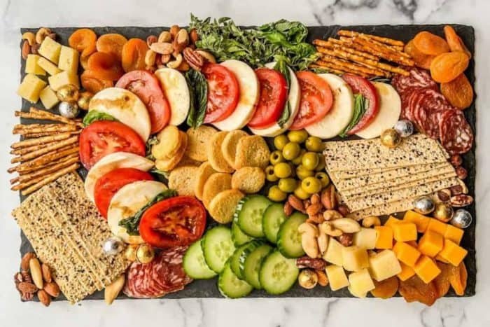 beautifully curated Christmas charcuterie board is here, including a thoughtful selection of cheeses, meats, olives, crackers, pretzel sticks, and dried fruits