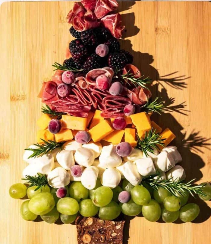 The towering tree offers rows of green grapes, marshmallows, cheese, salami, coppa meat, cranberries, and blackberries, with a brownie trunk.