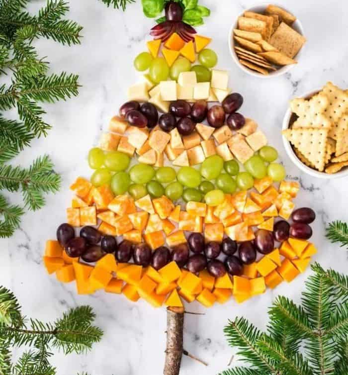 christmas tree cheese platter alternates between rows of cheeses and grapes to form a Christmas tree, where the star is a creatively fanned-out grape