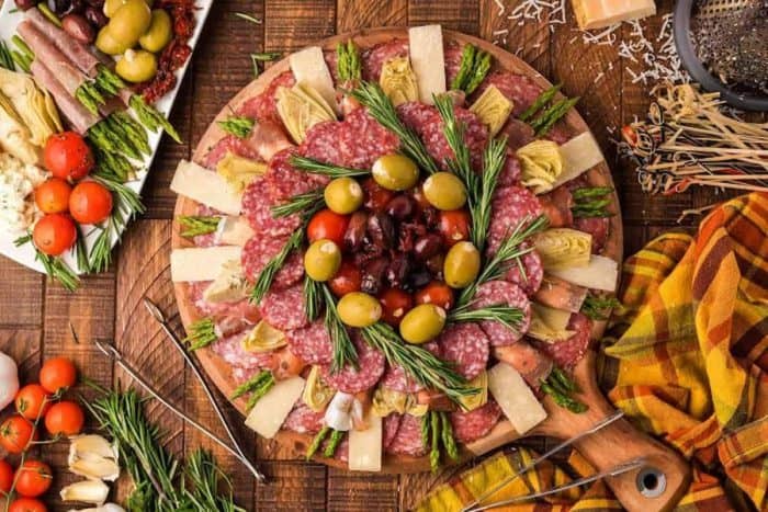 Italian charcuterie board, which features olives, tomatoes, artichoke hearts, asparagus, and deli meats