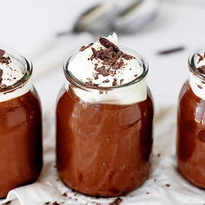 mason jars full of chocolate pudding topped with whipped cream