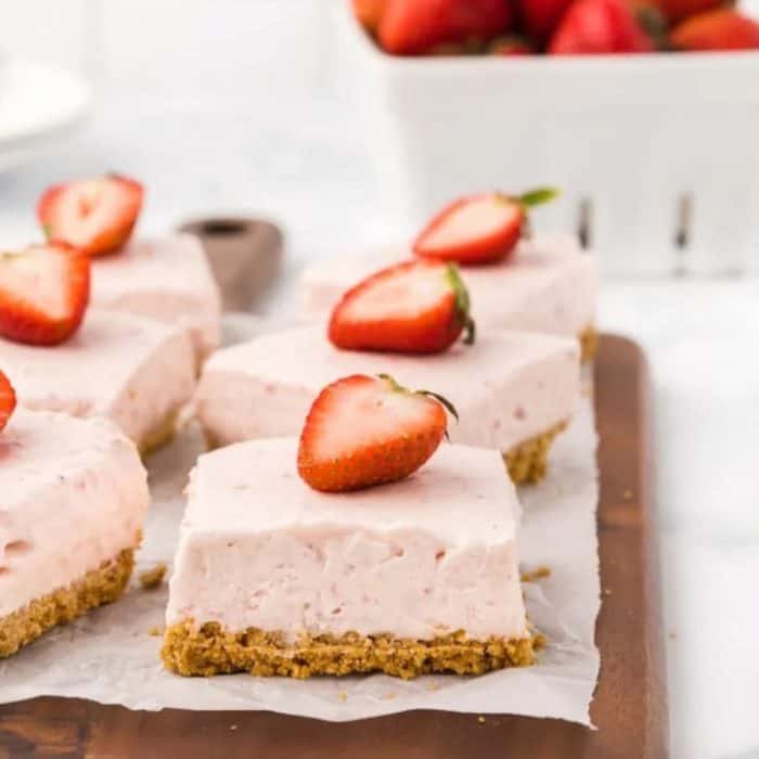 No-bake strawberry cheesecake bars present a velvety eggless cheesecake filling mixed with a generous helping of strawberry puree, set atop a crumbly graham cracker base.