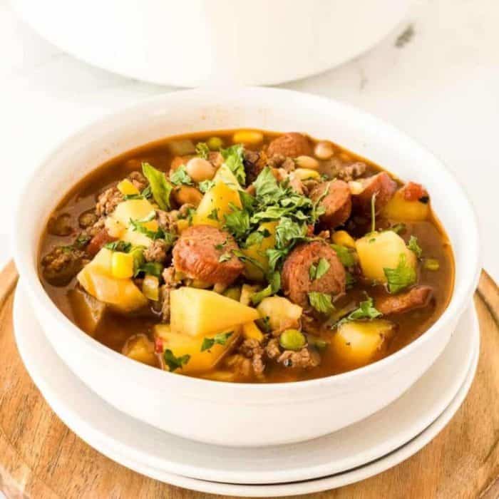 Cowboy Stew is a robust soup featuring ground beef, kielbasa, bacon, and hearty vegetables, making it ideal for feeding a crowd or serving on a chilly day.