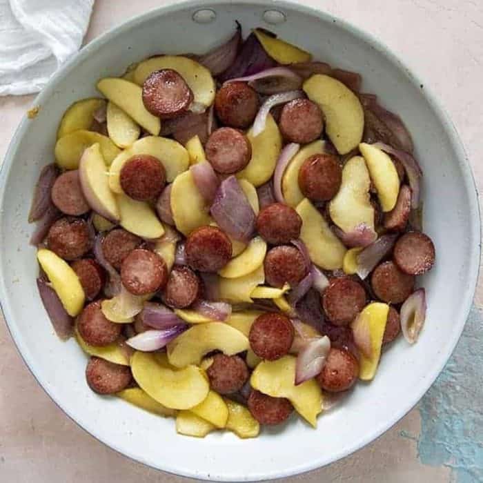 The combination of kielbasa with thinly sliced apples and red onions creates a savory and slightly sweet dish.