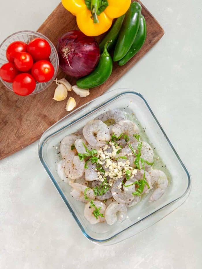 In a bowl, combine the shrimp with minced garlic, chopped basil, lemon juice, olive oil, sea salt, and pepper to taste.