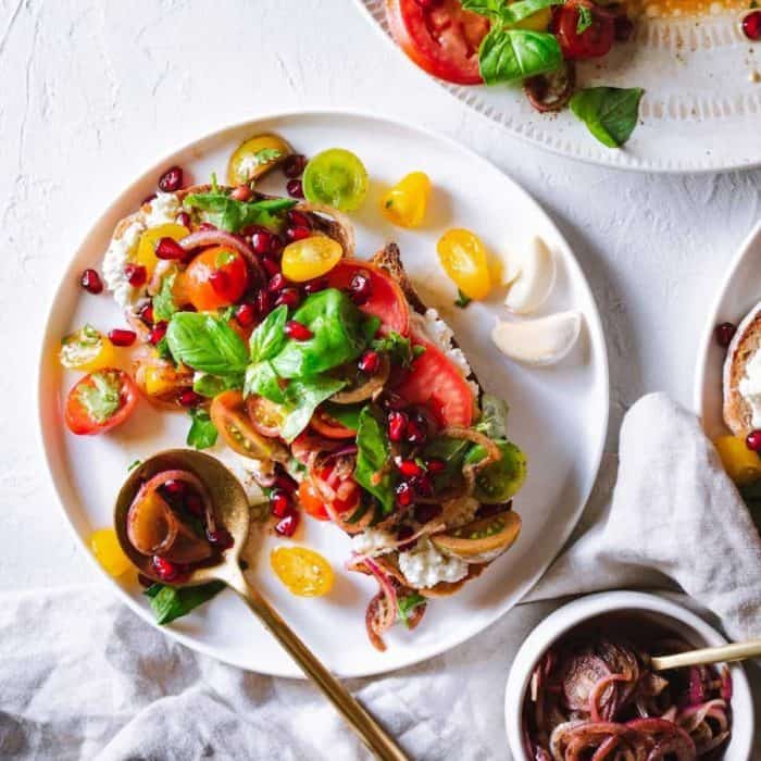 Here’s a vibrant salad that showcases the lush sweetness of tomatoes, the herbaceous taste of basil, and the jewel-like burst of pomegranate seeds.