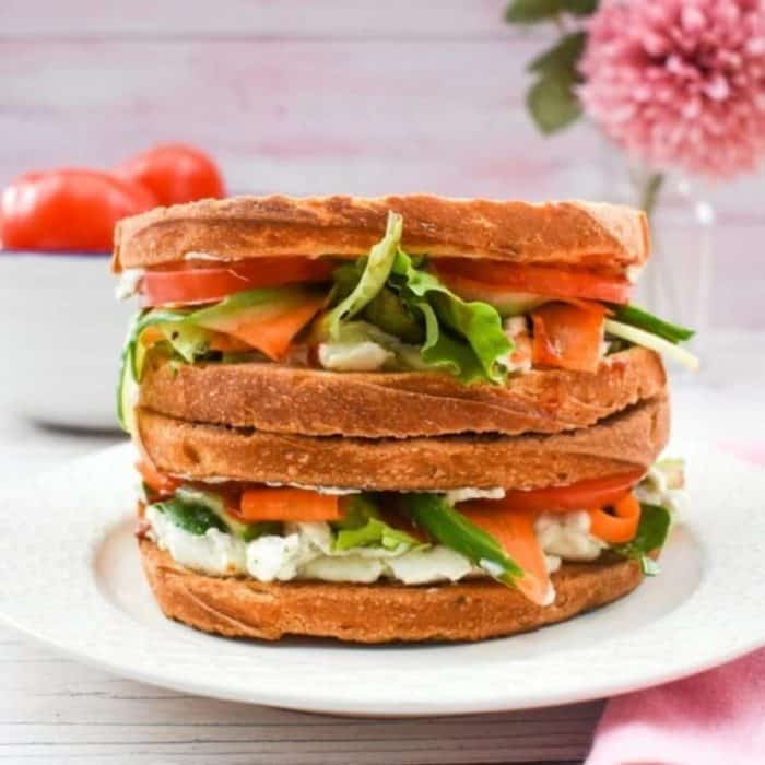 two layers of pickled veggies sandwiches on a white round plate