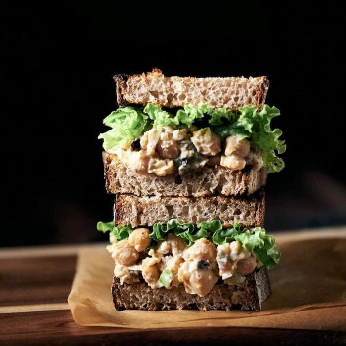 a photo of two layers of vegan chickpea salad sandwich on a black background