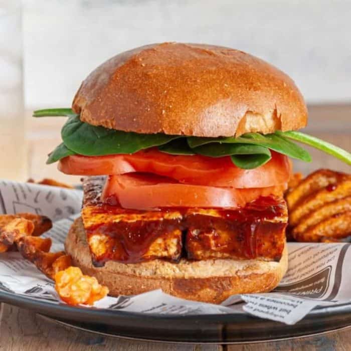 a close up photo of crispy bbq tofu sandwich on a plate
