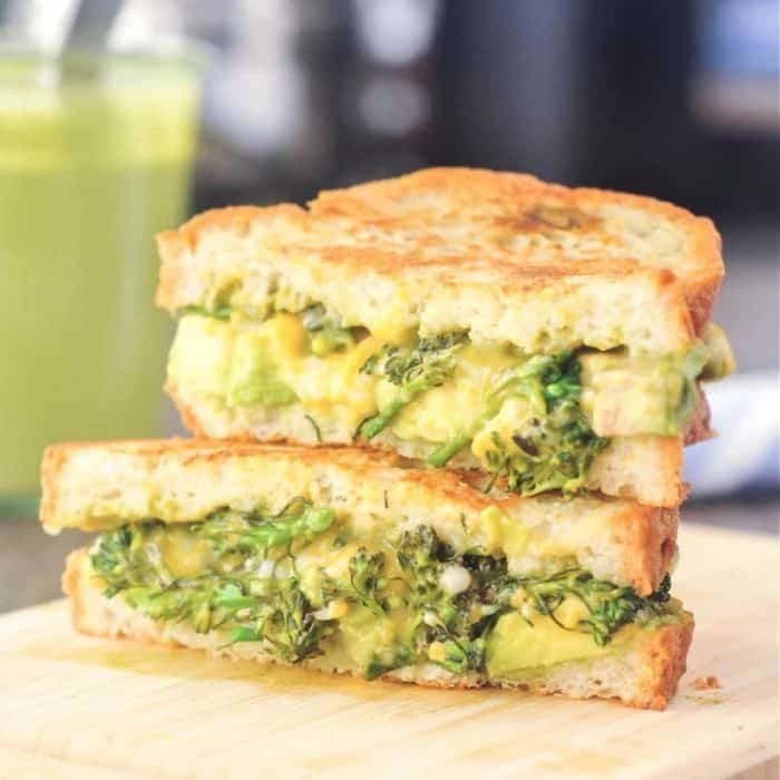 two pieces of green goddess grilled cheese sandwich on a wooden chopping board