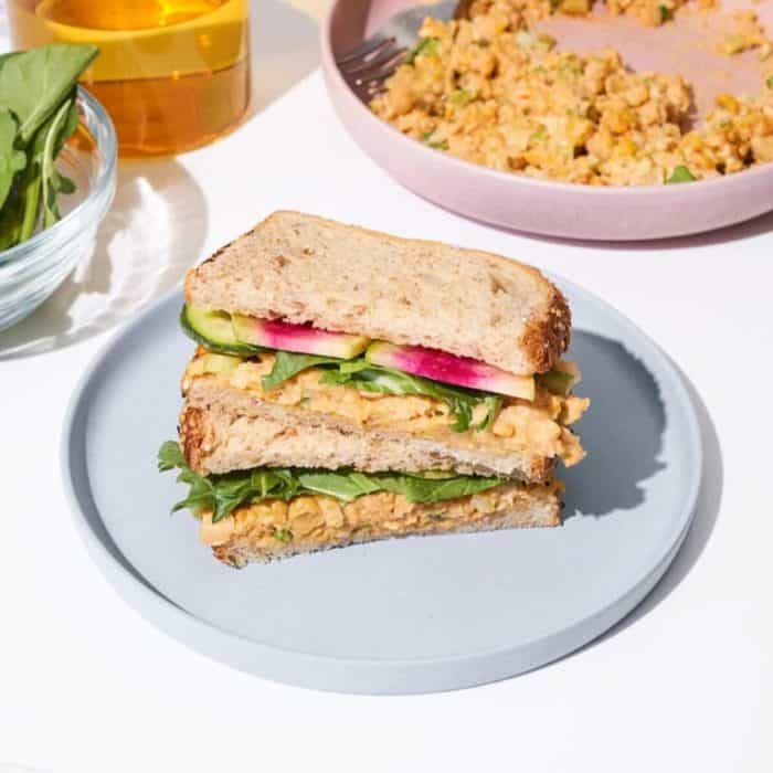 a photo of a slice of spicy chicken sandwich on a gray round plate on top of a white table