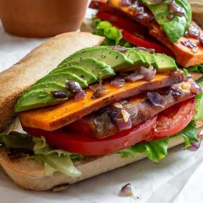 a close up photo of sweet potato and avocado sandwich on a white table