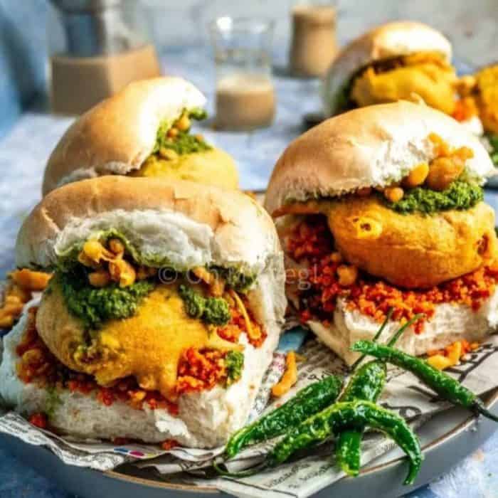 two pieces of overload vada pav vegan sandwich on a plate