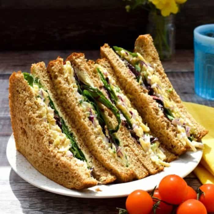 three slices of vegan cheese and onion sandwich on a white round plate