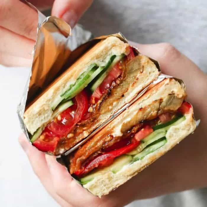 a woman's hands holding a vegan sandwich eggplant