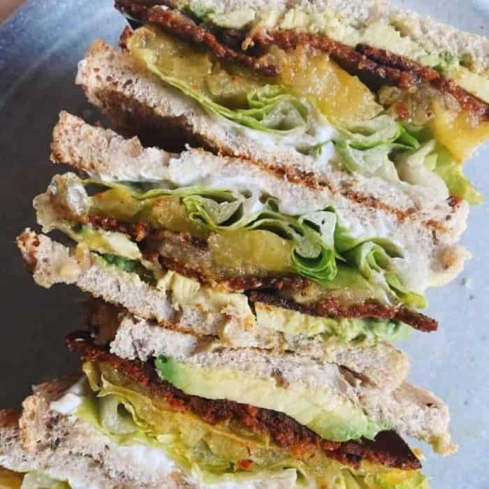 a close up photo of several layers of blat sandwiches with heirloom tomatoes