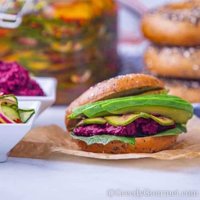 a photo of a hummus burger sandwich on a top of a white table with couple of sandwiches on the background