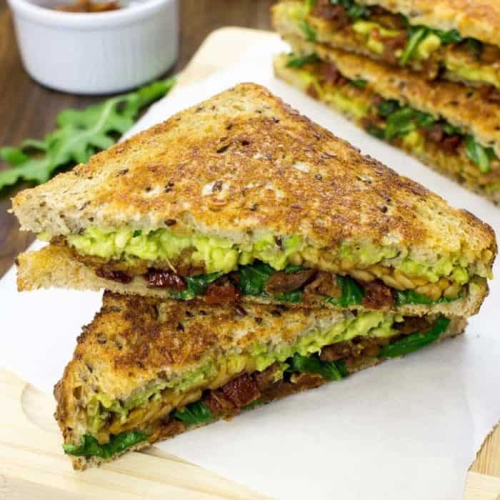 two slices of vegan tempeh sandwich on a white surface