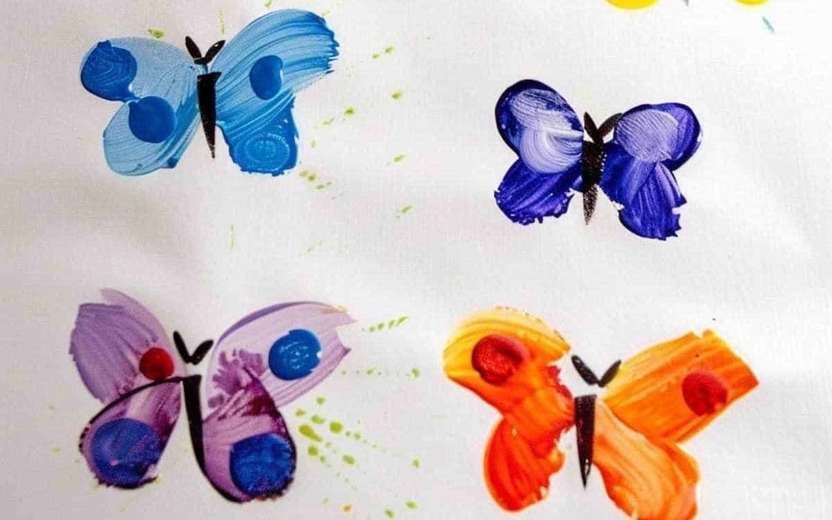 A finger painting of colorful butterflies on white paper, with splotches of paint for the details