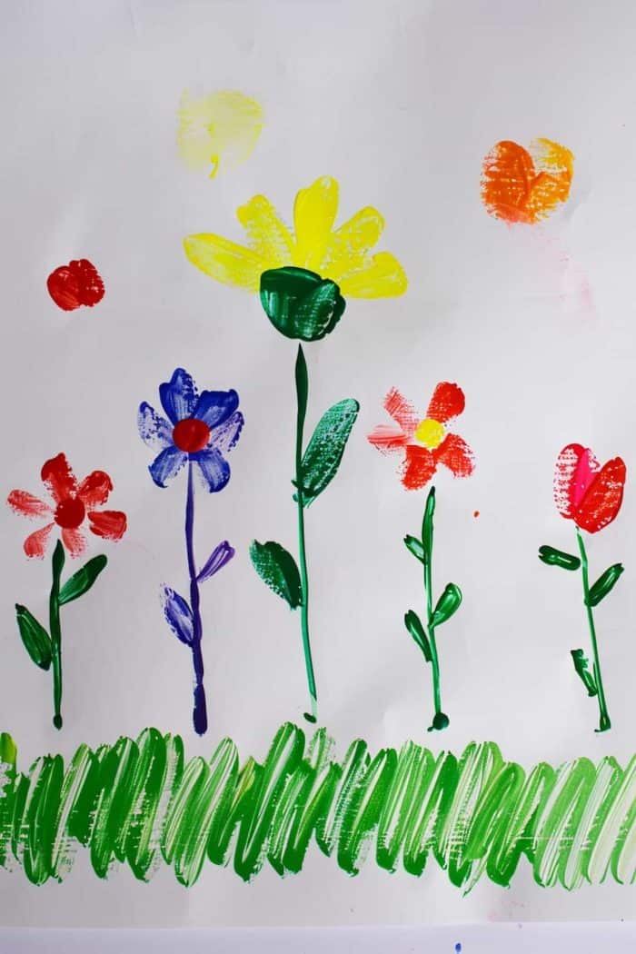 A finger painting of flowers in a field, with stems painted using a brush