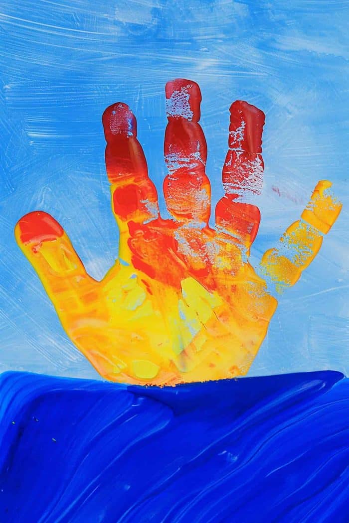Craft a sunrise scene by applying a mix of warm colors to the hands, like red, orange, and yellow to represent the rising sun. 