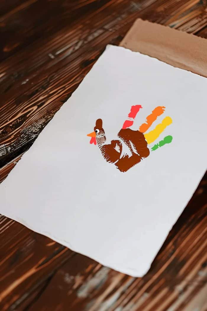 Form turkeys with multicolored handprints as feathers, using brown for the body, and red, orange, and yellow for the feather tips. 