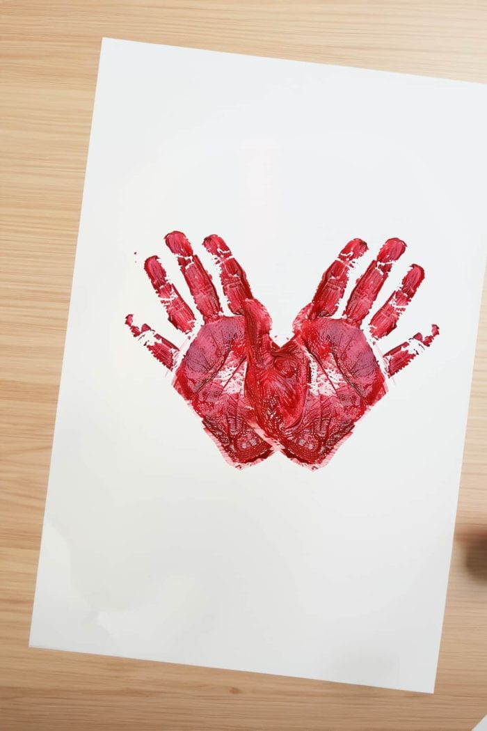 Craft Valentine's cards by positioning red or pink handprints with the heels touching and fingers outstretched to form a heart shape. 