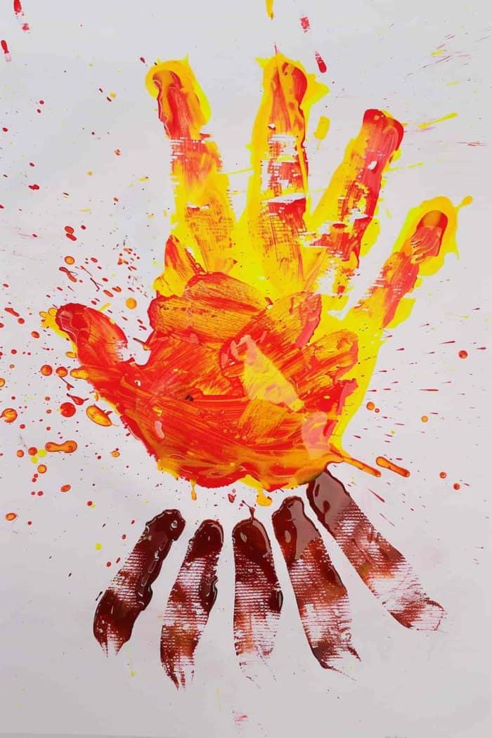 Capture the warmth of a campfire with overlapping orange and red handprints on a sheet of paper, enhanced with finger-painted details. Kids can apply brown paint to their fingers and press them onto the sheet to paint logs for a realistic appearance.