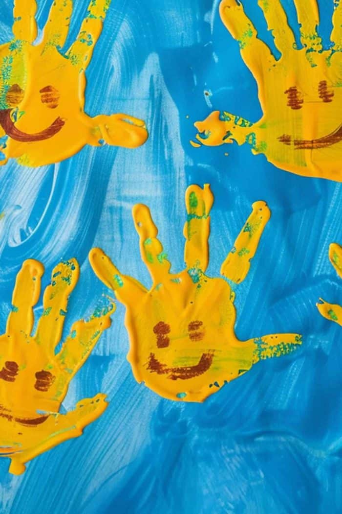 This painting of cheerful suns is made with bright yellow handprints, using the fingers as rays. 