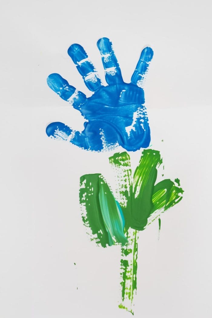 Create a vibrant flower using a handprint as the blossoms. Use fingers to paint petals, stems, and leaves to complete the look, crafting a cheerful and colorful bloom on paper.