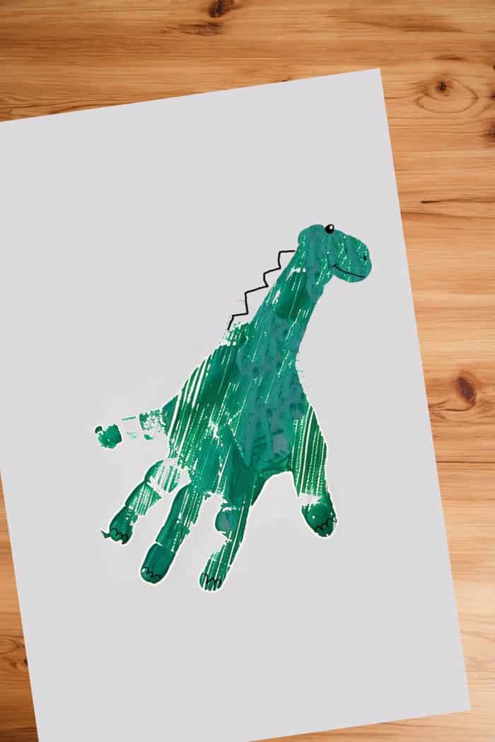 Develop a prehistoric landscape with handprints in bold colors to form dinosaurs of different species. Use a brush to add details like a head, spikes, stripes, or wings to the handprints.