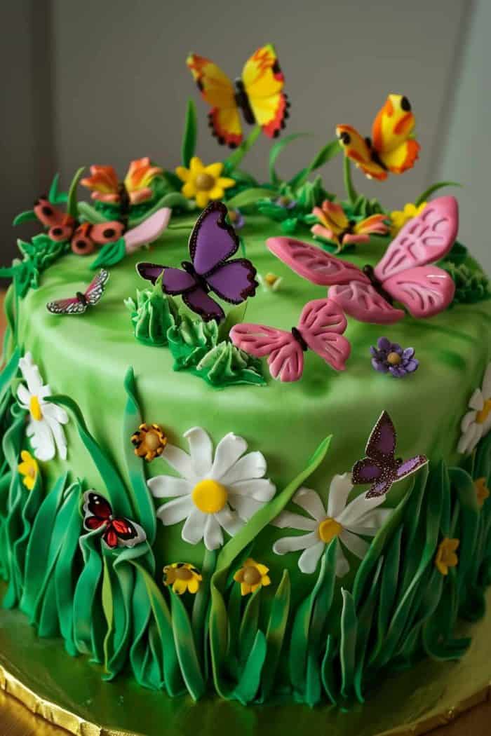 Transform your cake into a vibrant meadow by decorating it with green buttercream to mimic lush grass. Scatter small fondant flowers and butterflies throughout the grassy landscape, creating a lively and enchanting scene. Use a variety of flower shapes and butterfly colors to add depth and interest.