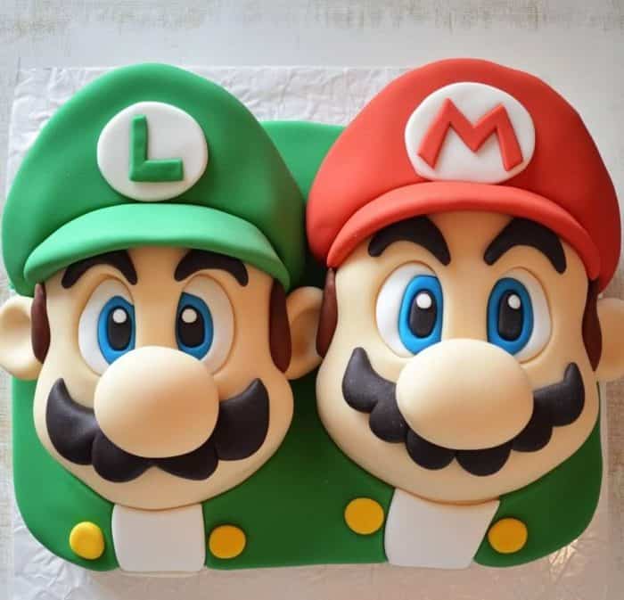 A cake designed to resemble two video game characters with large mustaches and hats labeled "L" and "M". The left side is green, and the right side is red.