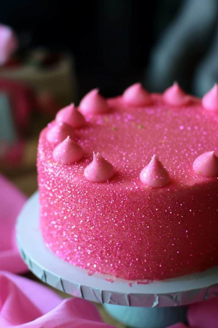 A dazzling pink shimmer cake featuring a smooth layer of pink buttercream icing, dusted with pink edible shimmer powder for a sparkling, glamorous finish. The subtle glimmer catches the light beautifully, making this cake ideal for elegant events such as weddings, anniversaries, or any occasion where a touch of sparkle and sophistication is desired.