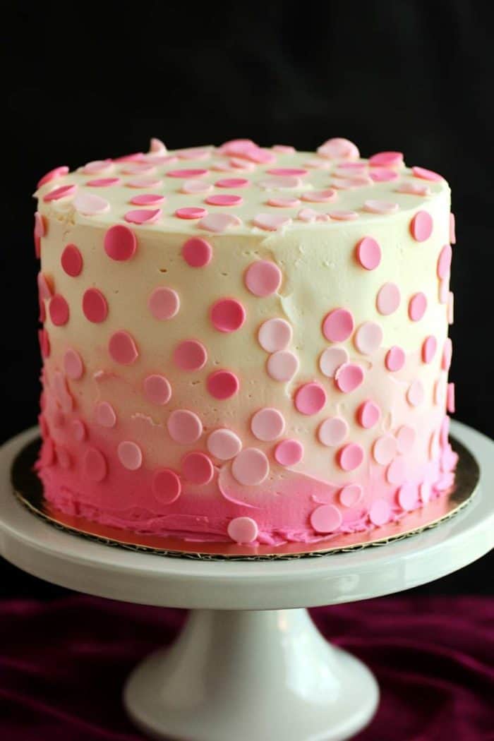 A playful pink polka dot cake featuring a smooth layer of white or light pink buttercream icing. Polka dots in various shades of pink are created using a stencil or freehand technique, adding depth and interest to the design. This cheerful cake is perfect for birthdays and baby showers, bringing a fun and festive touch to any celebration.