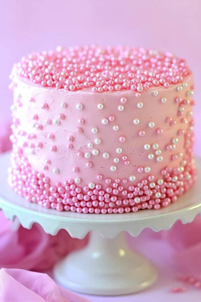 An elegant pink pearl cake covered with a smooth layer of pink buttercream or fondant. Edible pink pearls are meticulously placed all over the cake, either in a uniform pattern or clustered for a dynamic look. The pearls add a classic touch of beauty, making this cake perfect for weddings, bridal showers, or any special occasion where a timeless design is desired.