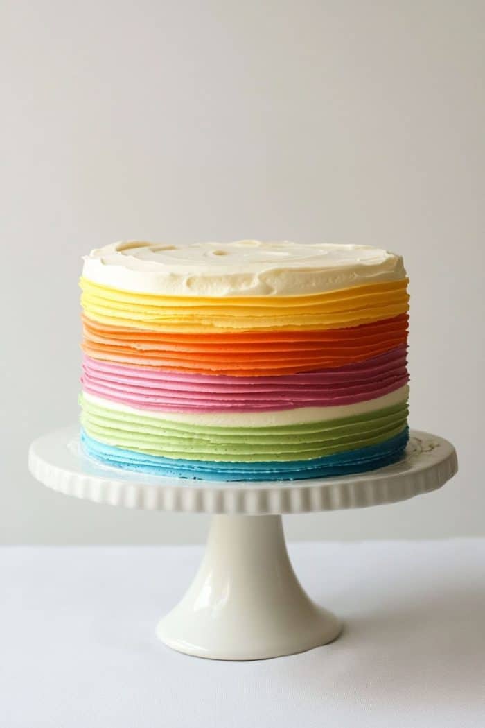 For a sleek and modern take on the classic rainbow cake, try a minimalist rainbow stripe cake. Start by frosting your cake with a smooth layer of white buttercream to create a clean canvas. Then add textured stripes in rainbow colors around the sides of the cake.