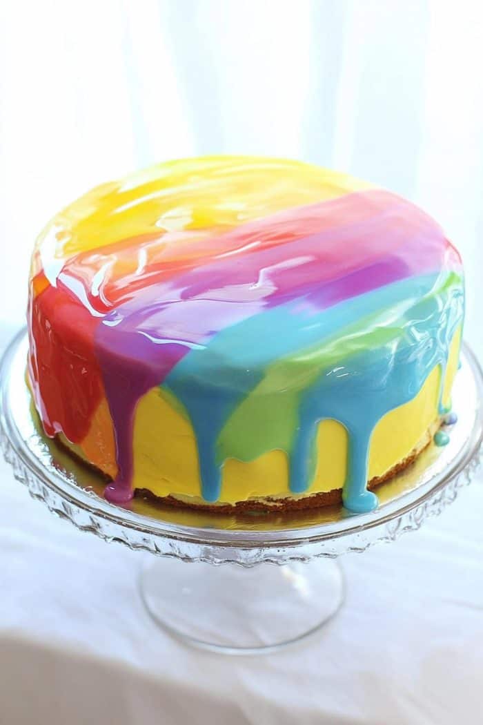 A glossy mirror glaze in rainbow colors exudes modern sophistication with a joyful vibe! Recreate this by making a mirror glaze, dividing it into separate bowls, and dyeing each one a different color of the rainbow. Carefully pour the glaze over the cake to let the colors blend in a mesmerizing way.