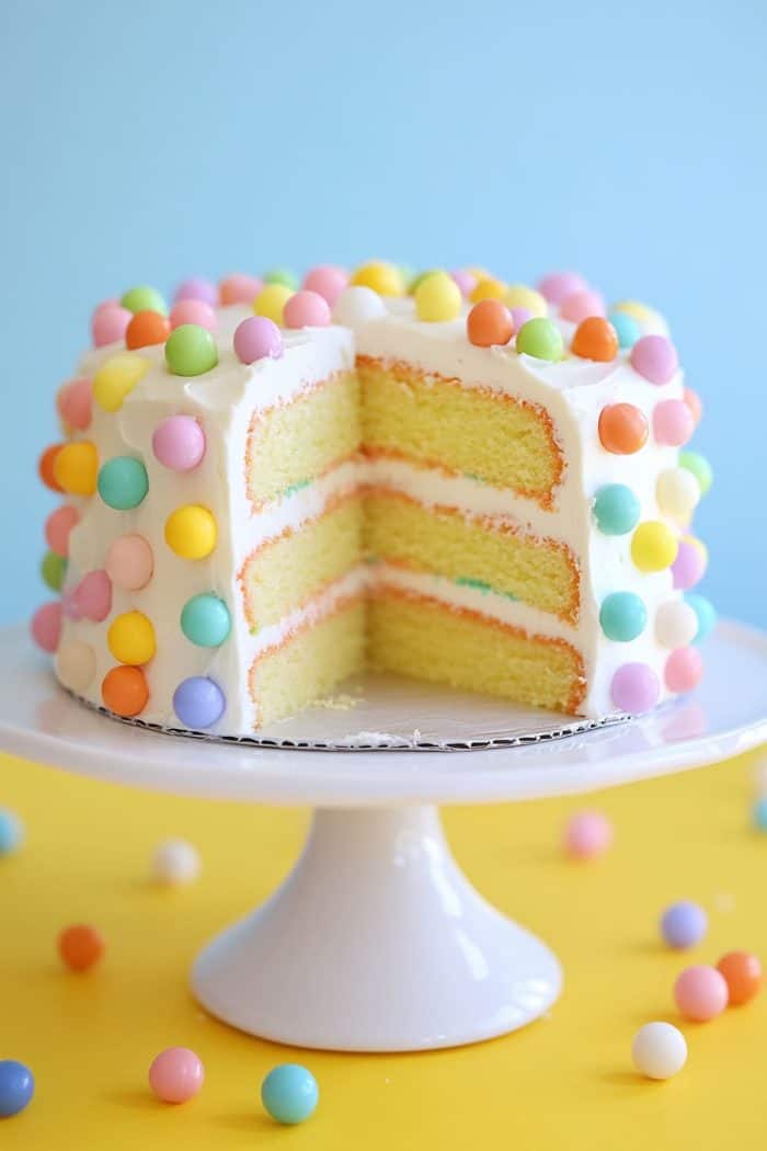 Enjoy a playful cake with a pastel polka dot pattern! To achieve this whimsical design, place pastel-colored candies on a cake with smooth white buttercream frosting.