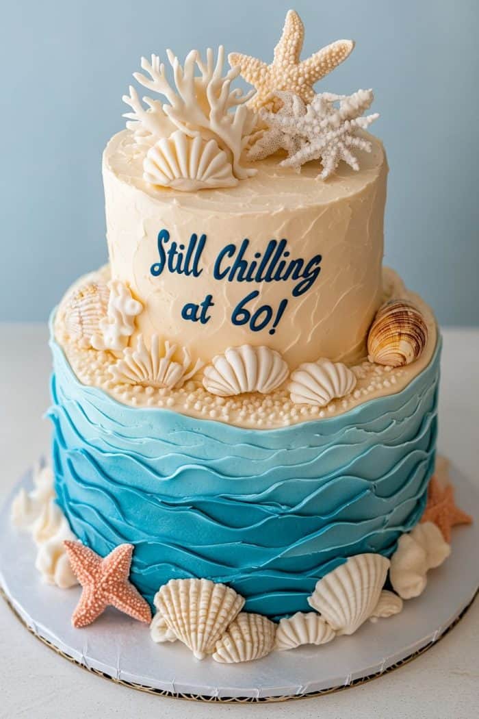 A two-tier cake with an ocean theme, featuring starfish, seashells, and coral decorations. The top tier is cream-colored with the text "Still Chilling at 60!" The bottom tier has blue waves.
